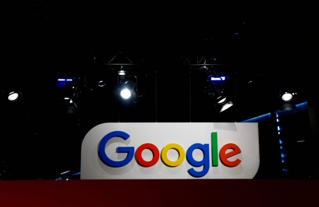 Logotipo colorido do Google em um palco escuro, iluminado por holofotes.