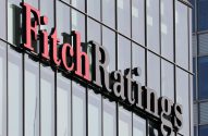 Letreiro "Fitch Ratings" vermelho e preto, 3D, em uma fachada moderna de prédio de vidro.