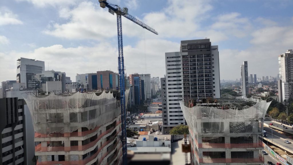 Vista aérea de cidade em construção com arranha-céus e guindaste.