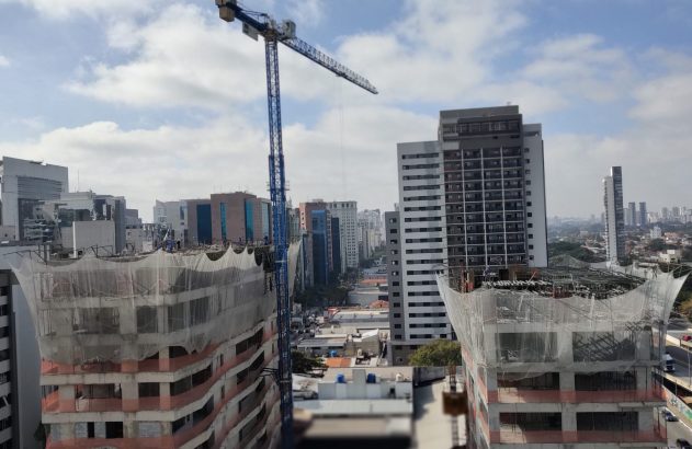 Vista aérea de cidade em construção com arranha-céus e guindaste.
