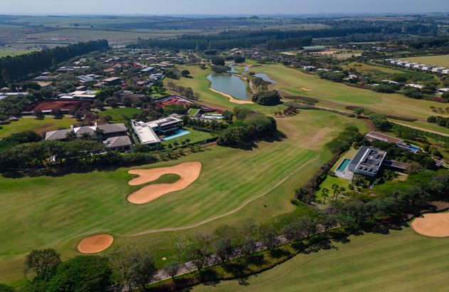 Vista aérea de campo de golfe com lago e casas do Fazenda Boa Vista: destino dos muito ricos