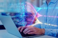 Pessoa digitando em laptop com dados e fluxos digitais coloridos, representando processamento de informação.