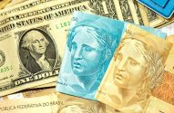 Cédulas de dólar americano e real brasileiro, com moeda e cartões de crédito.