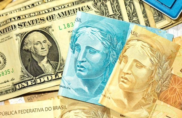 Cédulas de dólar americano e real brasileiro, com moeda e cartões de crédito.