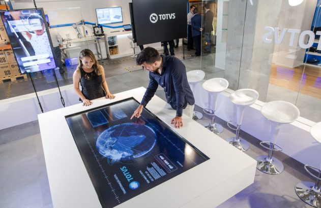 Mãos digitando em um teclado de notebook retroiluminado em azul.