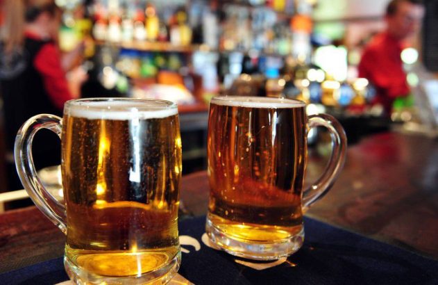 Dois canecos de cerveja em um balcão de bar.