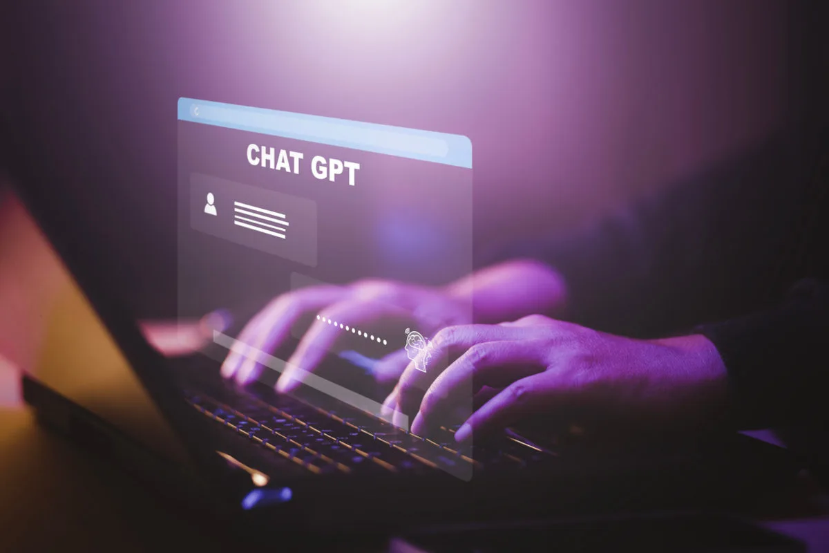 homem teclando em um notebook, com uma projeção virtual do chat gpt