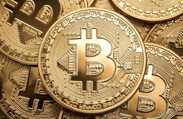 Moedas douradas de Bitcoin empilhadas, com a principal exibindo o símbolo 'B' e padrões de circuito.