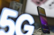 Um smartphone com tela colorida em exibição. À esquerda, um grande letreiro luminoso branco com "5G".