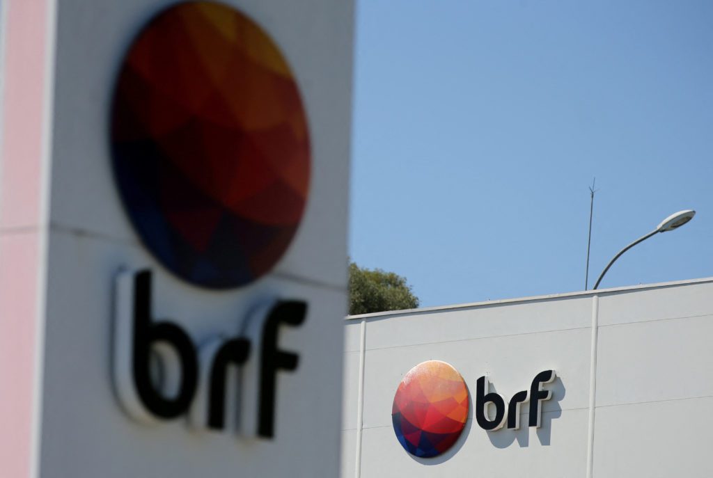 Logotipo da empresa BRF, com círculo colorido, em um edifício branco sob céu azul.