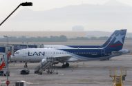 Dois aviões da LAN em um aeroporto. Um deles está no portão de embarque, com montanhas nebulosas ao fundo.