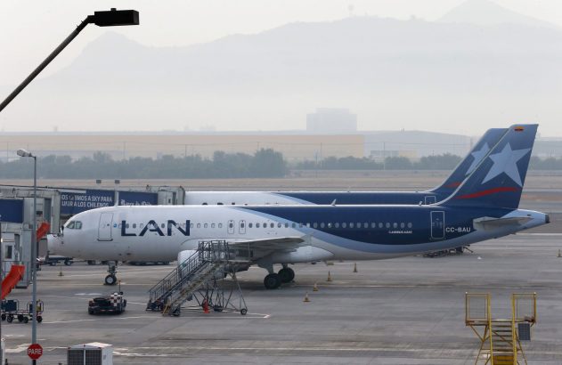 Dois aviões da LAN em um aeroporto. Um deles está no portão de embarque, com montanhas nebulosas ao fundo.