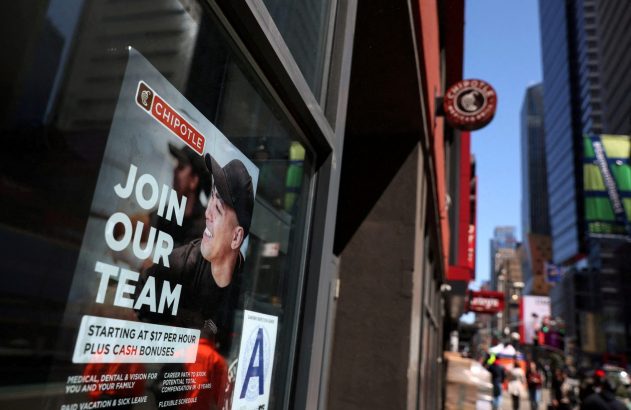 Cartaz 'Junte-se à nossa equipe' do Chipotle na vitrine de um restaurante. Destaca salário de US$17/hora e benefícios.