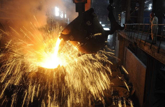 Metal fundido incandescente sendo vertido, gerando faíscas intensas em siderúrgica.