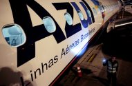 Lateral de avião da AZUL Linhas Aéreas em solo noturno. Um funcionário inspeciona a fuselagem com luz.