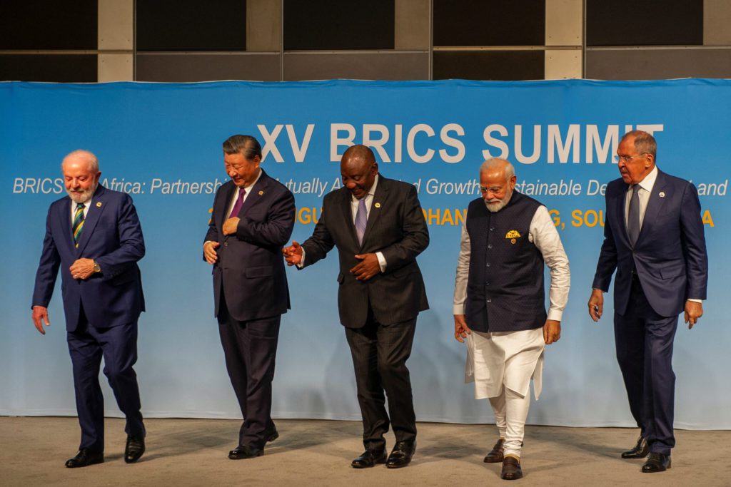 Cinco líderes do BRICS (Lula, Xi, Ramaphosa, Modi, Lavrov) sorrindo e caminhando no XV BRICS Summit.