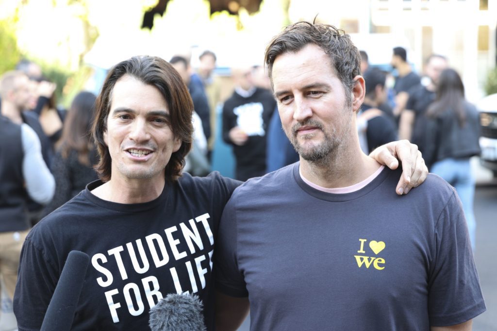 Dois homens sorrindo para a câmera. Um usa camisa "STUDENT FOR LIFE", o outro o abraça pelo ombro. Fundo com pessoas.