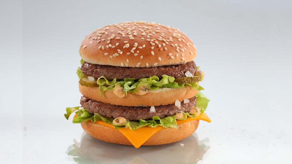 Big Mac: pães, duas carnes, queijo, alface, picles, cebola e molho especial. Fundo branco.