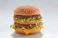 Big Mac: pães, duas carnes, queijo, alface, picles, cebola e molho especial. Fundo branco.