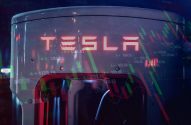 Carregador Tesla com logo em destaque e dados de mercado de ações sobrepostos.