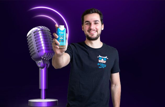 Homem sorridente apresenta bebida azul. Microfone e ondas sonoras roxas no fundo.