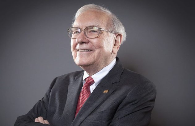 Retrato de homem idoso sorrindo, usando óculos, terno escuro e gravata vermelha, com os braços cruzados.