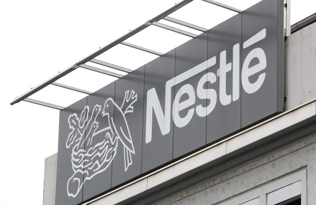 Sinal da Nestlé em prédio, com logo de ninho e pássaros e nome da empresa.