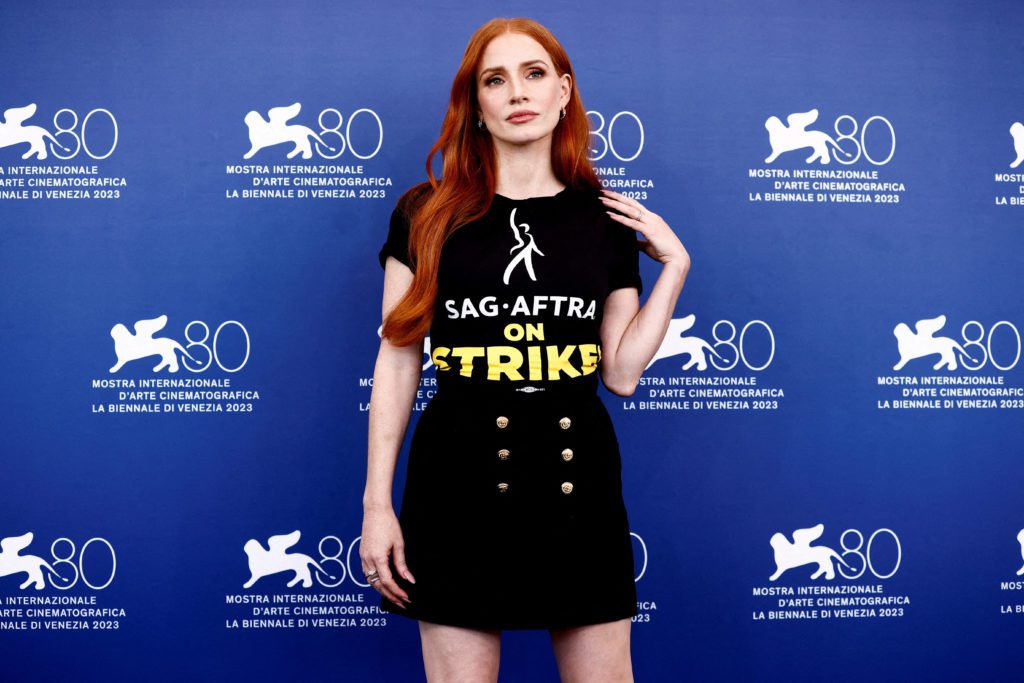 Atriz Jessica Chastain, ruiva, posa com camiseta "SAG-AFTRA ON STRIKE" no Festival de Cinema de Veneza.
