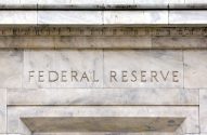 Nome "FEDERAL RESERVE" gravado na fachada de mármore de um edifício, com detalhes arquitetônicos.