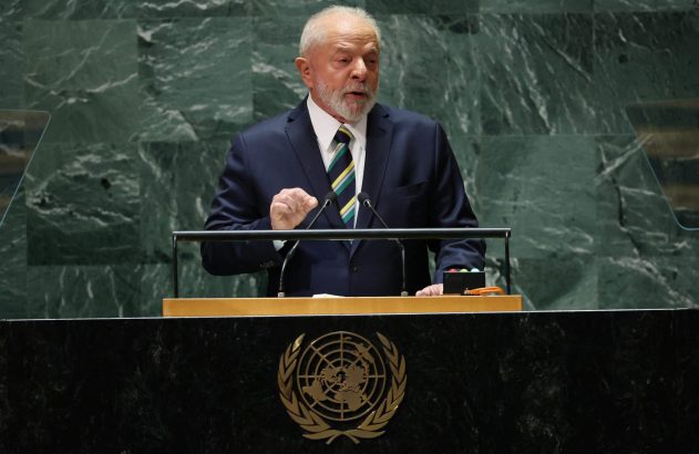 Homem de terno e gravata, com barba, discursa em púlpito da ONU. Mão levantada, microfones à frente.