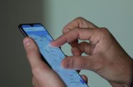 Mãos de pessoa usando smartphone, interagindo com mapa em aplicativo de navegação.