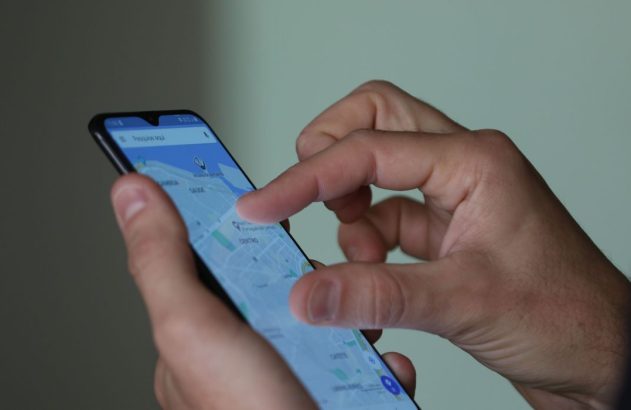 Mãos de pessoa usando smartphone, interagindo com mapa em aplicativo de navegação.