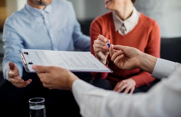 casal recebendo um seguro prestamista, com a mulher rexebendo também uma caneta em sua mão