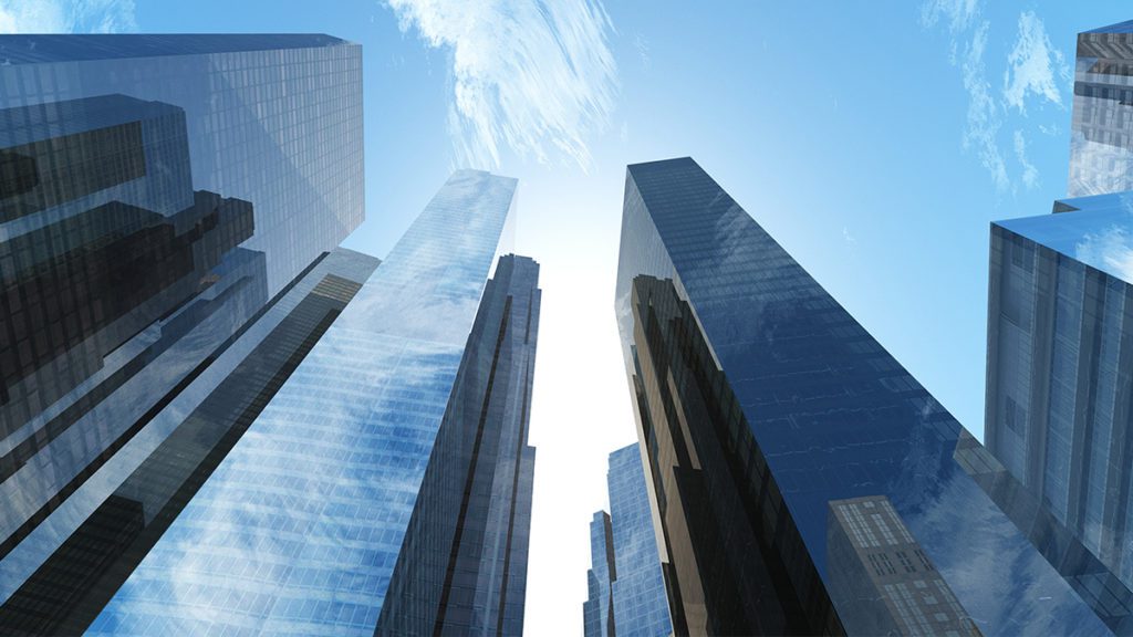Arranha-céus modernos vistos de baixo para cima contra o céu azul.