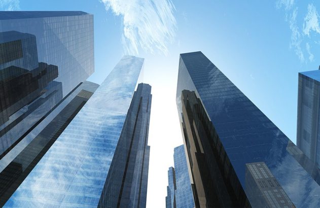 Arranha-céus modernos vistos de baixo para cima contra o céu azul.