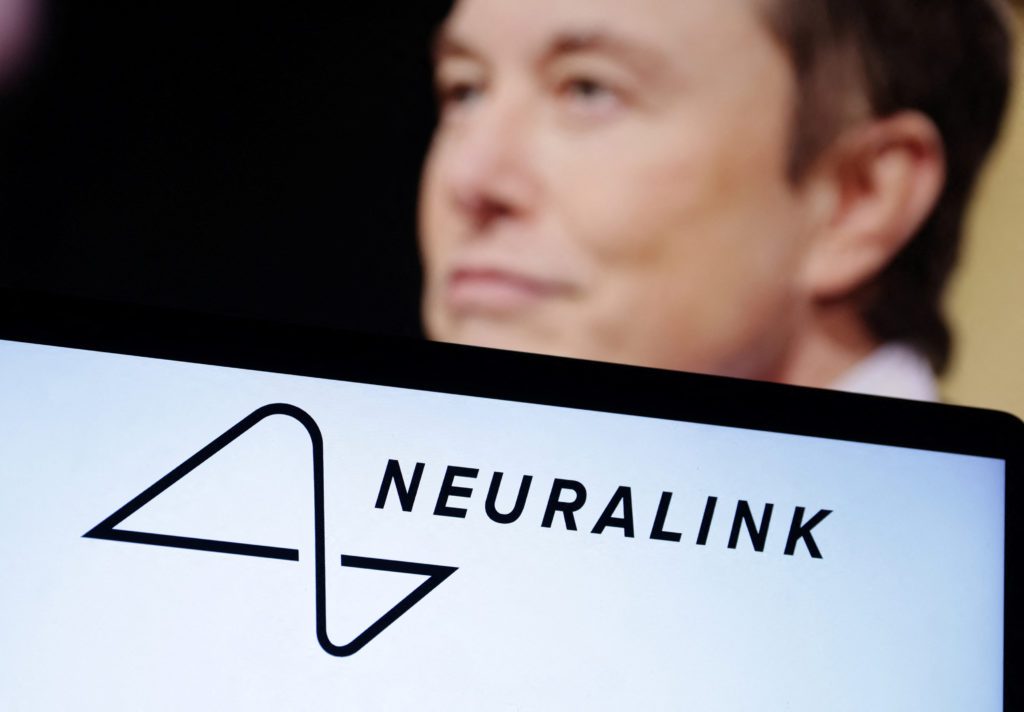 Tela com logo e nome "NEURALINK"; Elon Musk desfocado em segundo plano.