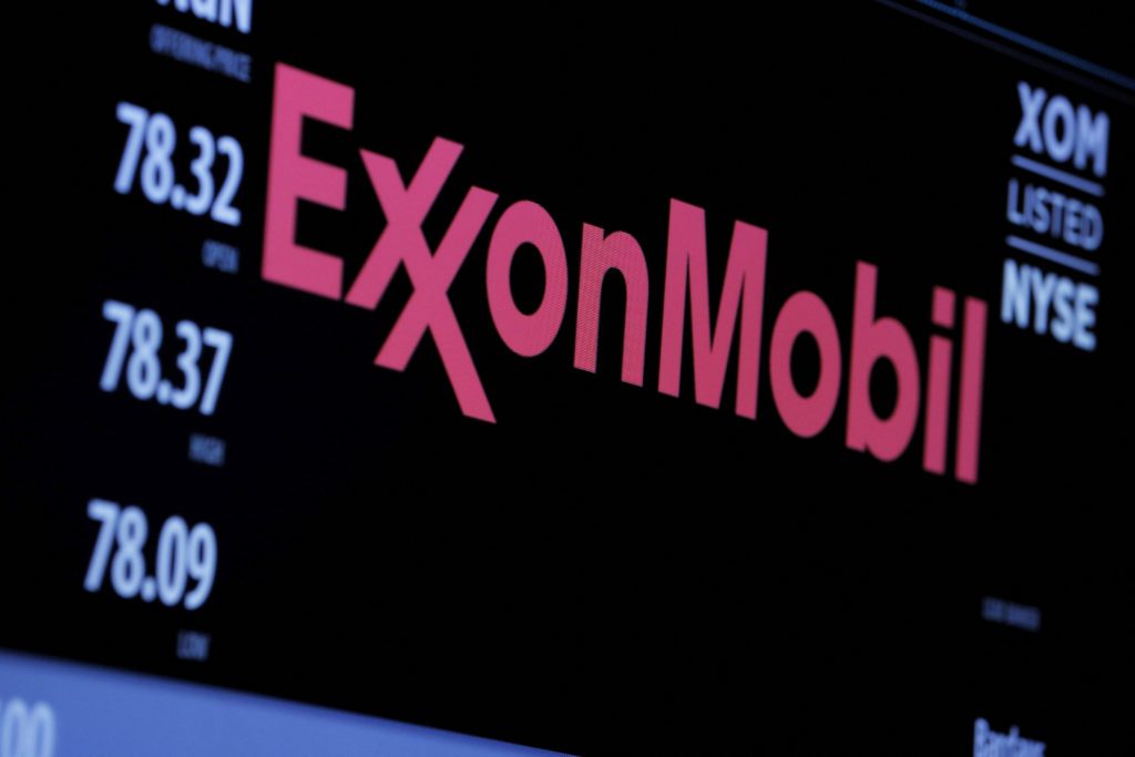 Painel digital exibe ExxonMobil e cotações da empresa XOM na NYSE, com números de abertura, alta e baixa.
