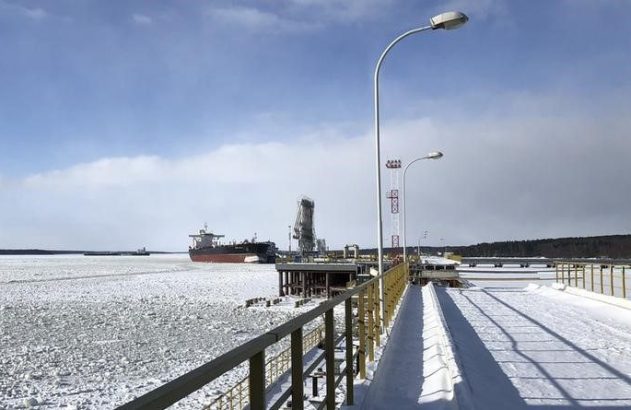 Navio em terminal portuário de inverno. Água com blocos de gelo e passarela coberta de neve.