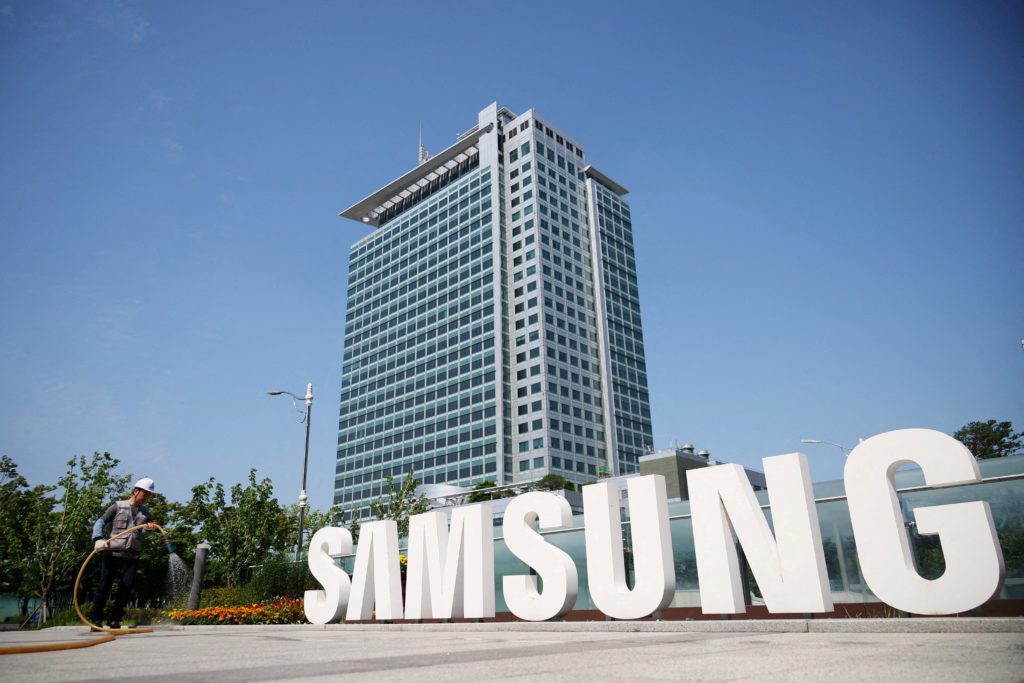 Sede da Samsung, letreiro da marca e jardineiro regando flores.