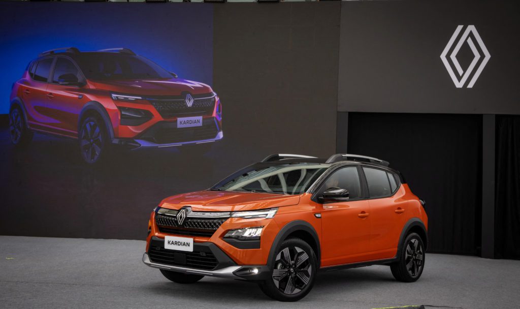 Renault Kardian laranja em evento, com imagem do carro e logo Renault em telas.