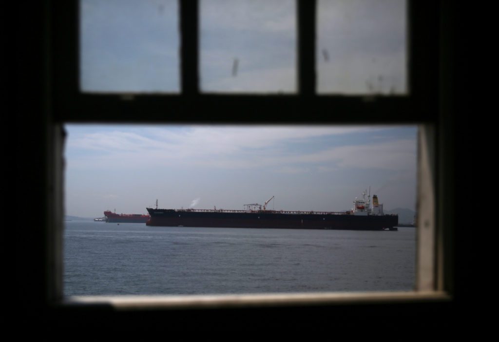Navio cargueiro no mar, visto por uma janela com moldura escura.
