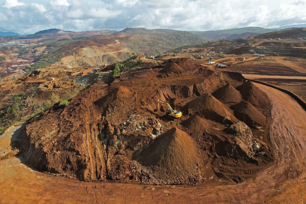 Grandes pilhas de minério avermelhado em uma mina a céu aberto. Paisagem industrial.