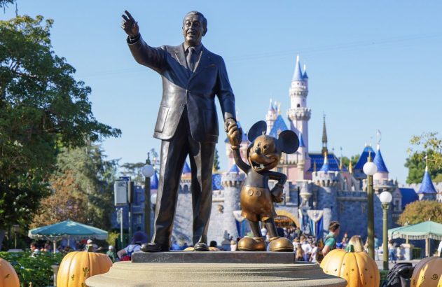 Estátua "Partners" de Walt Disney apontando e Mickey Mouse, com Castelo da Bela Adormecida e abóboras.