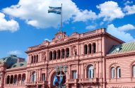 Casa Rosada, palácio presidencial da Argentina, sob céu azul com nuvens e a bandeira argentina ao alto.