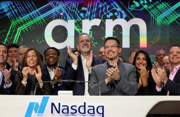 Pessoas aplaudem a listagem da Arm na Nasdaq, com o logo 'Arm' e o pódio 'Nasdaq' em destaque.