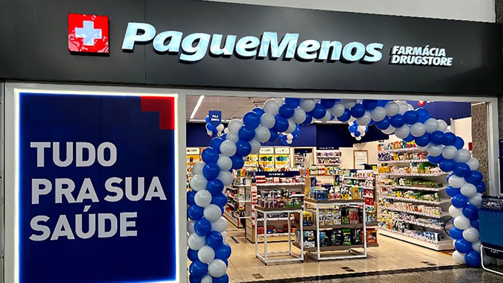 Pague Menos Farmácia Drugstore. Entrada com arco de balões azuis e brancos. Placa "Tudo pra sua saúde".
