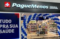 Pague Menos Farmácia Drugstore. Entrada com arco de balões azuis e brancos. Placa "Tudo pra sua saúde".
