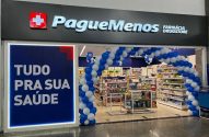 Entrada da Pague Menos Farmácia Drugstore com balões azul/brancos e cartaz 'Tudo pra sua saúde'.
