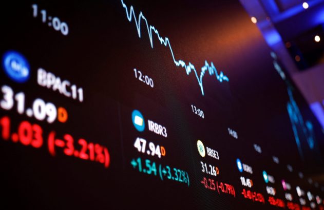 Tela digital do mercado de ações com gráfico de preços, cotações e horários. Valores em vermelho e verde.