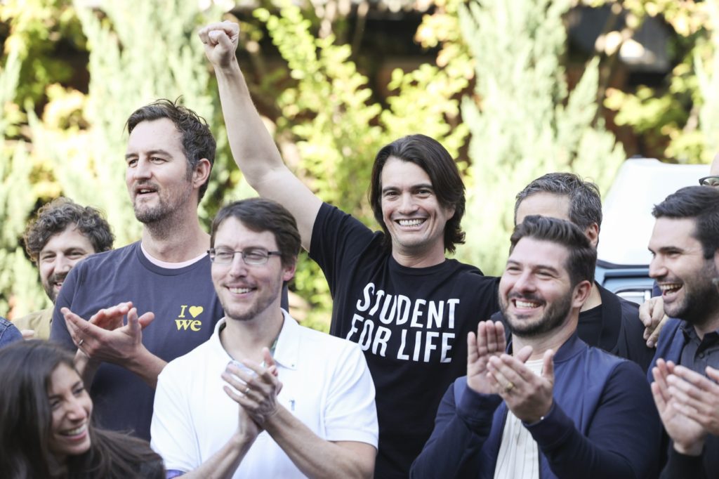 Grupo de pessoas, a maioria homens, sorrindo e aplaudindo ao ar livre. Um deles levanta o punho com camisa "STUDENT FOR LIFE".